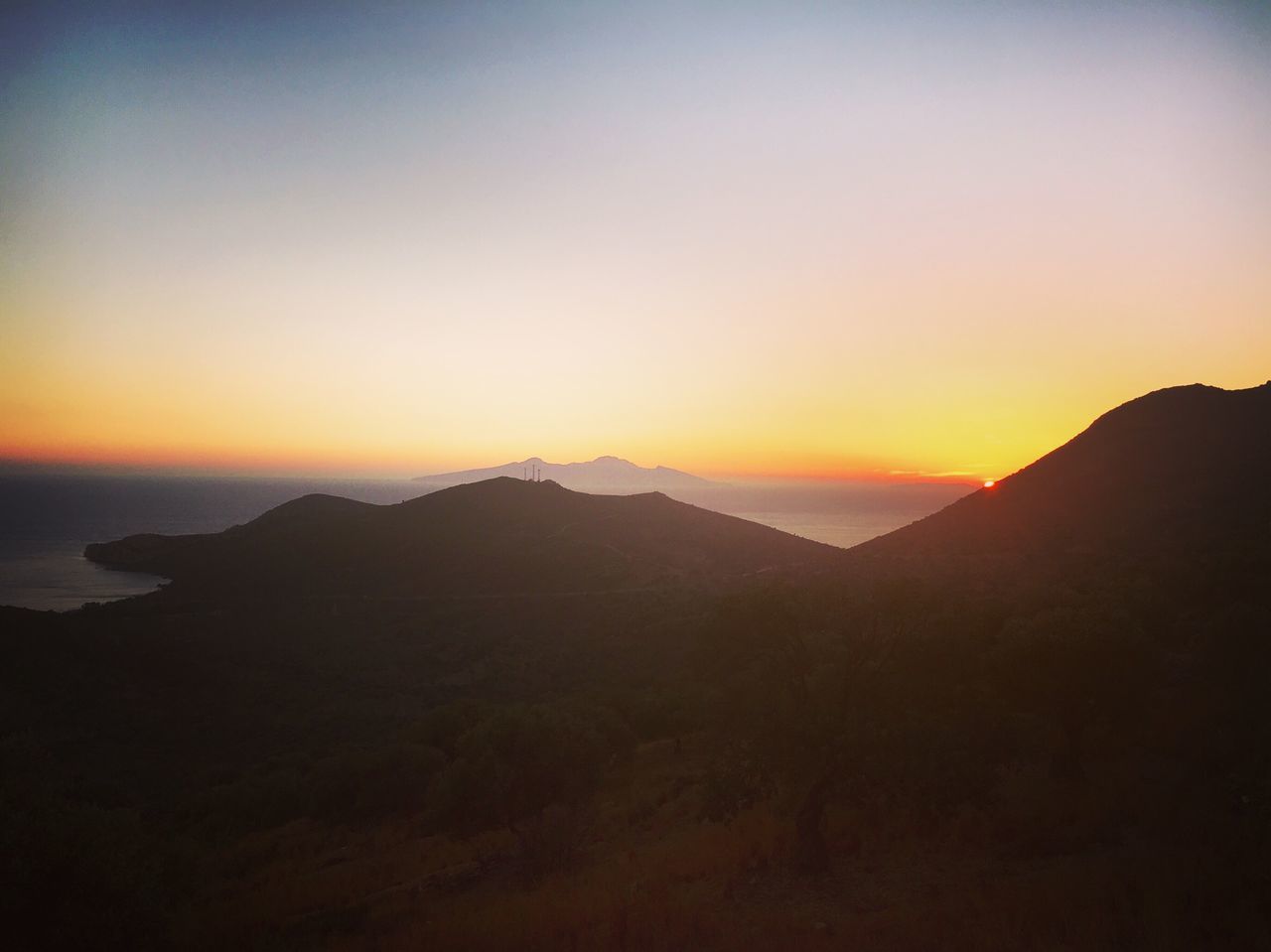 SCENIC VIEW OF SILHOUETTE MOUNTAINS AGAINST ORANGE SKY