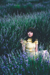 Woman standing by purple flowers on field