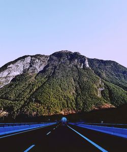 Road amidst trees against clear sky