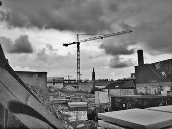 Low angle view of crane against cloudy sky