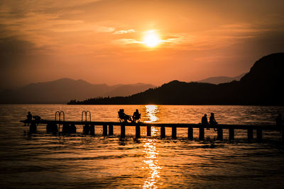 Silhouette of tourists in lake during sunset