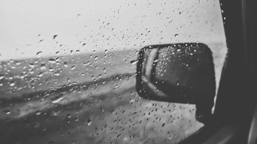 Close-up of wet glass against sky