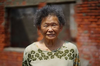 Portrait of smiling senior woman standing against building