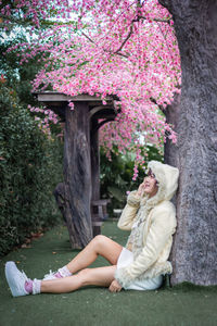 Side view of woman sitting on flowering plant