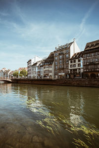 Bridge over river by buildings against sky