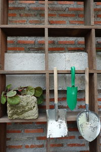 Potted plant on shelf against brick wall