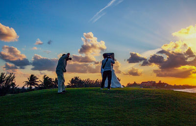 Man standing on golf course against sky during sunset