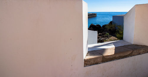 Buildings by sea against blue sky