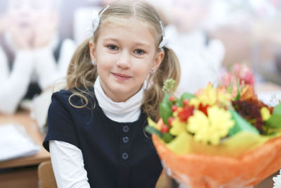 Portrait of cute girl sitting by flower