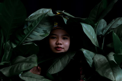 Portrait of young woman standing amidst plants