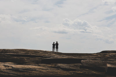 People standing on rock against sky