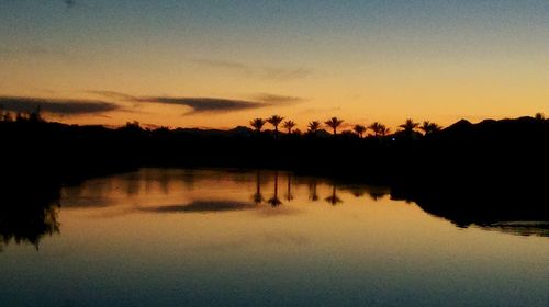 Reflection of trees in water at sunset