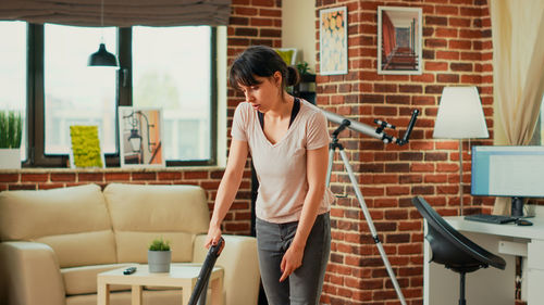 Side view of young woman using mobile phone while standing in office