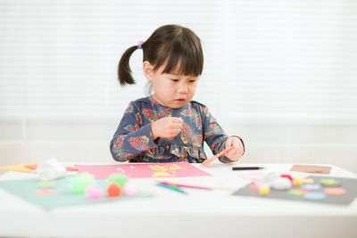 Girl playing at table against wall