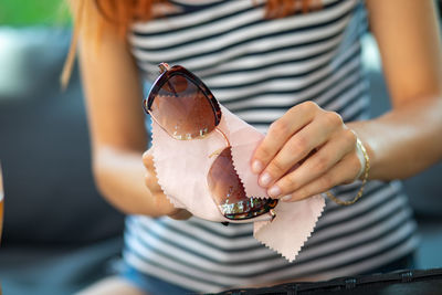 Midsection of woman cleaning sunglasses