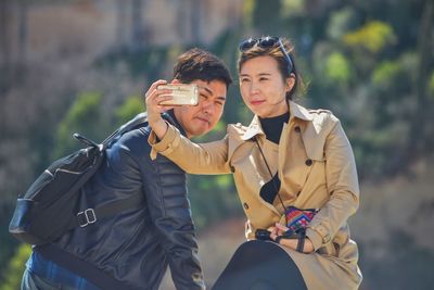 Young couple clicking selfie with smart phone outdoors