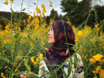 Midsection of girl looking at flowering plants on field