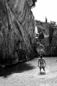 Rear view of man on bridge over river against sky