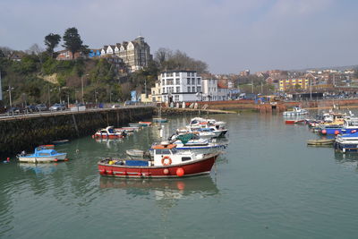 Boats in marina by buildings against sky