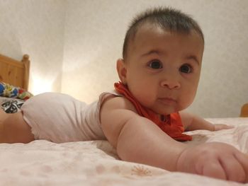 Portrait of cute baby lying on bed at home