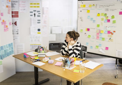 Businesswoman looking at reminders in creative office