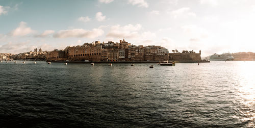 Buildings by sea against sky