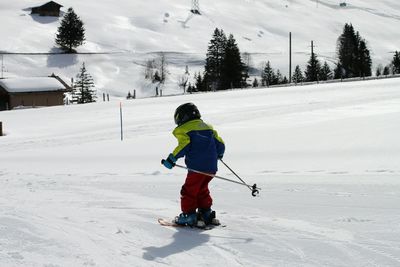 Rear view of boy skiing on snowcapped mountains