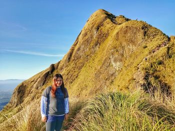 Portrait of smiling woman standing on land against sky