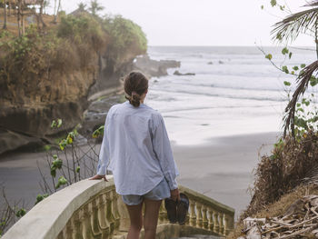 Rear view of woman walking down steps at beach