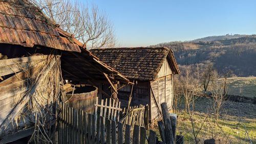 Bare trees in old building against clear sky