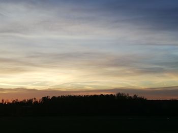 Silhouette trees on field against sky during sunset