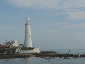 Lighthouse by sea against sky