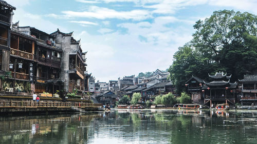 Buildings by lake against sky in city