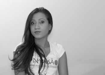 Portrait of young woman standing against white background