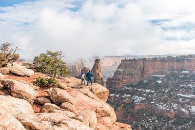 Hikers standing on cliff against sky