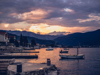 Sailboats moored on sea against sky during sunset