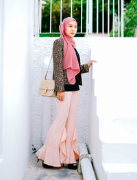 Woman wearing hat standing against wall