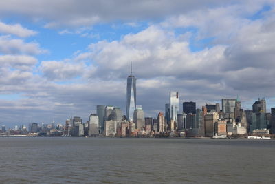 Sea by modern buildings against sky in city