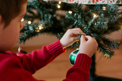 Young boy hanging decorations on a christmas tree