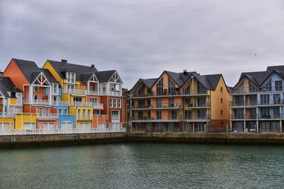 Residential buildings by river against sky