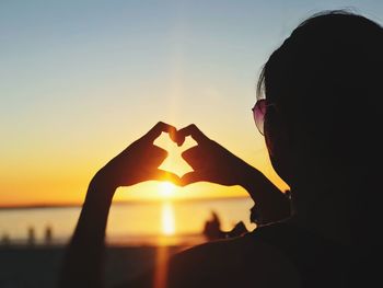 Portrait of silhouette woman with heart shape against sky during sunset