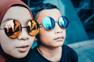 Close-up of siblings wearing sunglasses outdoors