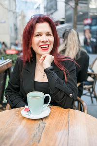 Young woman using mobile phone while sitting on table