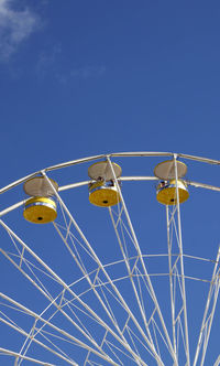 Low angle view of ferris wheel against blue sky