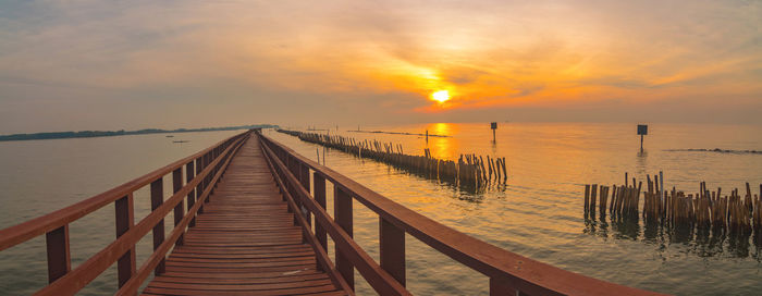 Pier over sea against sky during sunset