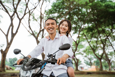 Portrait of smiling young woman riding bicycle on tree