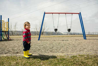 Side view of boy looking away while standing on field at park