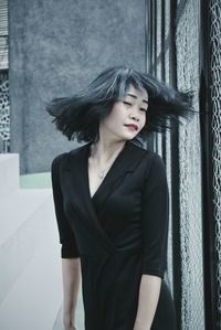 Portrait of young woman standing on wall