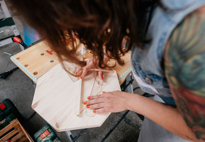 High angle view of woman measuring wood in workshop