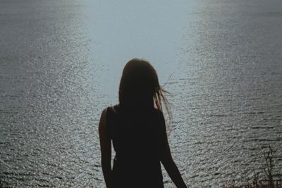 Rear view of silhouette woman standing at beach